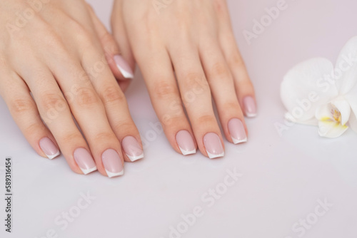 Perfect french manicure with flower in background.