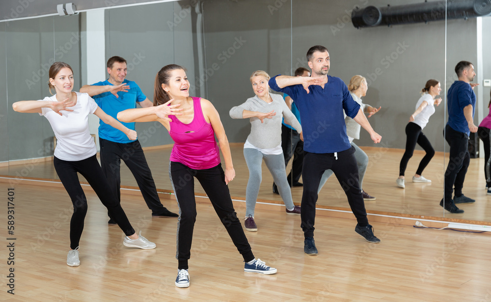 Portrait of dancing people practicing vigorous swing during group training in dance studio
