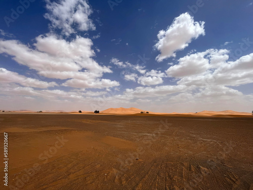 Merzouga  Morocco  Africa  panoramic road in the Sahara desert with view of the beautiful sand dunes  4x4 trip  blue sky and white clouds