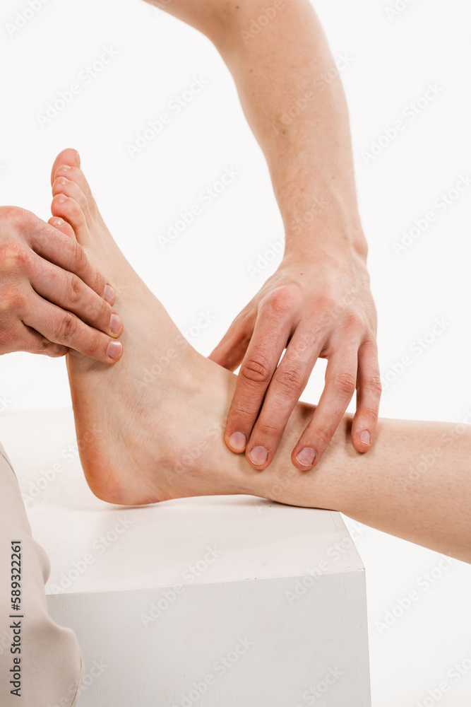 Fototapeta premium Foot close-up. Examination of ankle and foot mobilisations. Orthopedist is touching and pressing foot for assessment of the volume of physiological movements.