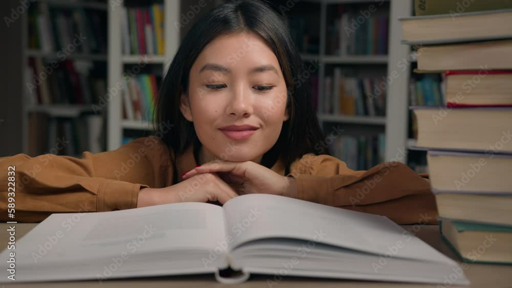 Close-up asian woman student read book in university library smiling girl lady reader enjoy reading novel literature looking at textbook studying information preparing for college exam doing homework Close-up asian woman student read book in university library smiling girl lady reader enjoy reading novel literature looking at textbook studying information preparing for college exam doing homework