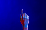 Exposed hand pointing finger in studio with blue light with copy space