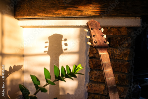 a vintage wooden guitar casting a shadow on rustic living room wall in sunlight