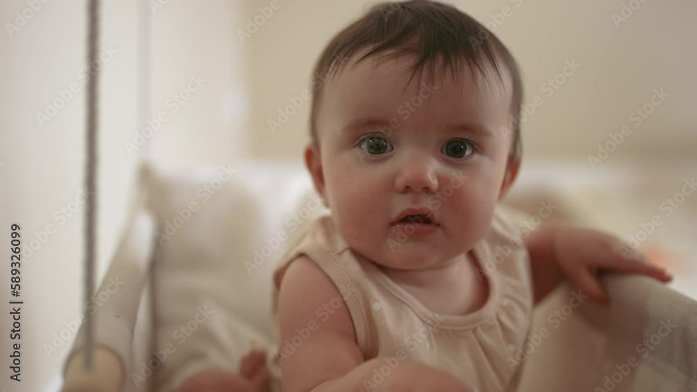 baby is swinging on a swing. baby blonde play at home sits on a rope swing. happy family kid