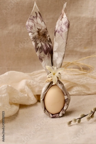 Wielkanoc i jajko w serwetce zapakowane jak zajączek wielkanocny. Wesoła ozdoba, akcesoria stołu