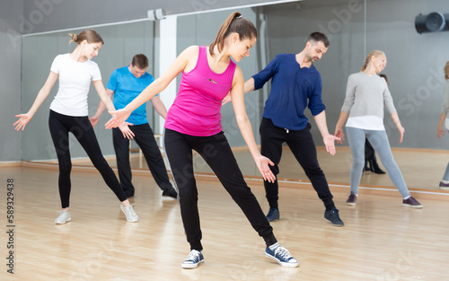 Smiling women and men of different ages warming up during dance class.