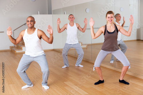 Group of happy adult people training movements of modern dance in choreography class