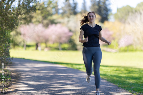 An adult smiling woman jogging on nature