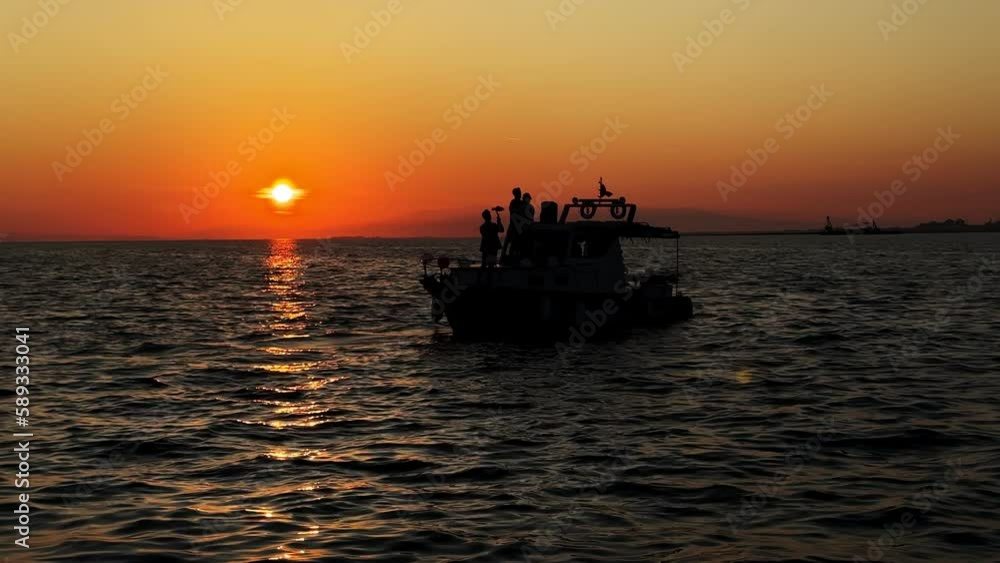 The Boat and People Silhouette in Sea in Sunset The Boat and People Silhouette in Sea in Sunset