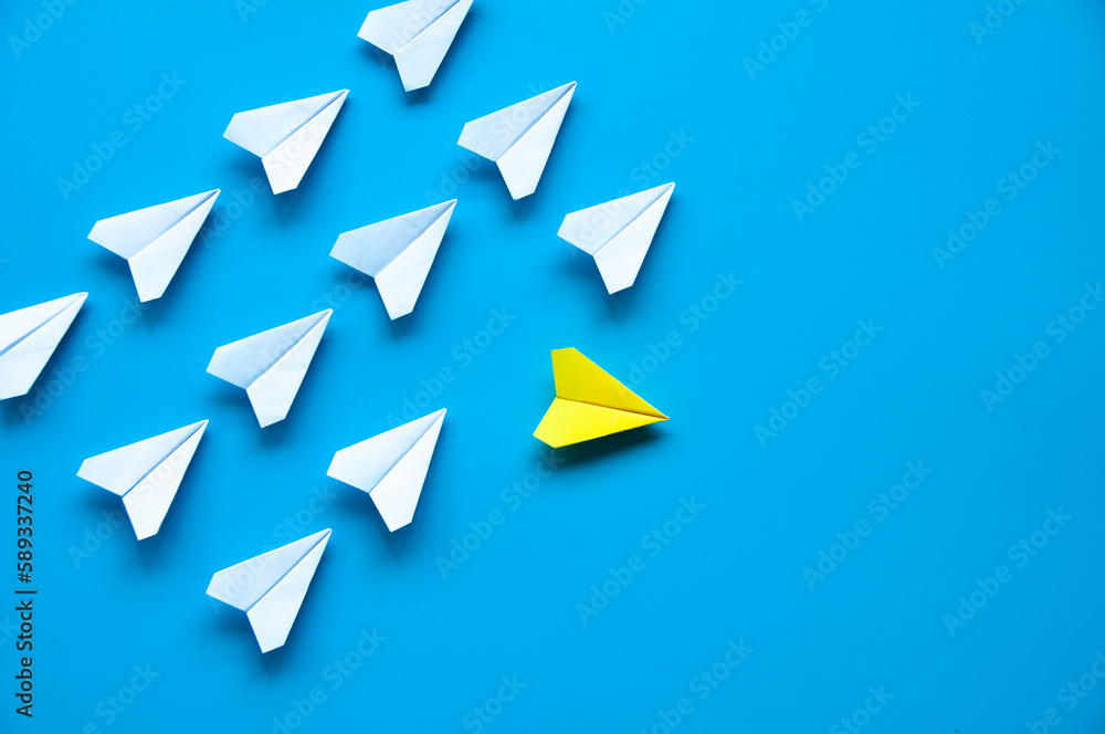 Yellow paper airplane origami leaving other white airplanes on blue background with customizable space for text or ideas. Leadership skills concept. Yellow paper airplane origami leaving other white airplanes on blue background with customizable space for text or ideas. Leadership skills concept.