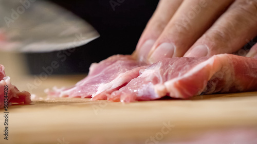 Close up of chef Butcher cutting pork meat with knife on kitchen, cooking food. The chef butcher preparing pork meat for cooking.