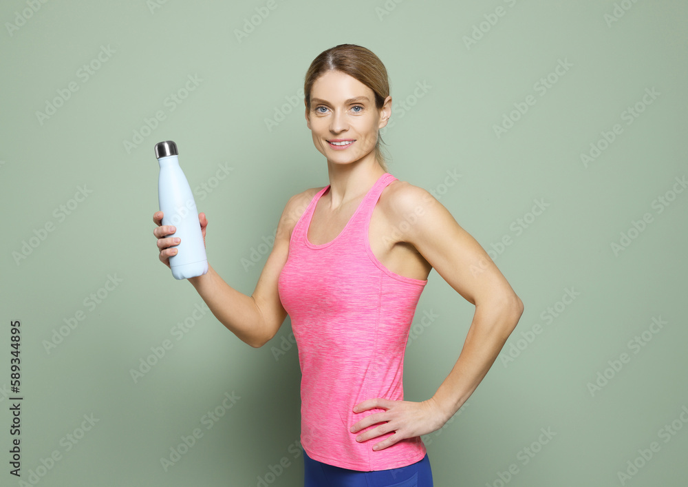 Sportswoman with thermo bottle on green background Sportswoman with thermo bottle on green background