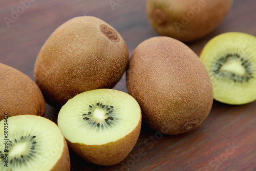 Whole and cut ripe yellow kiwis on wooden table, closeup