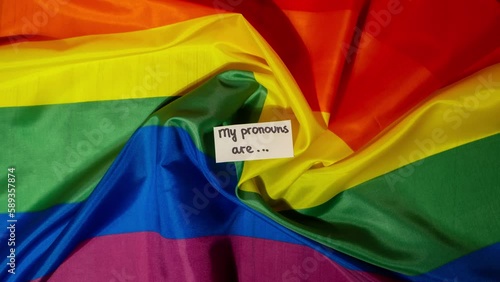 Stop motion of MY PRONOUNS ARE Neo pronouns concept. Rainbow flag with paper notes text gender pronouns hie, e, ne, xe, ze, tey. Non-binary people rights transgenders. Lgbtq community support assume photo