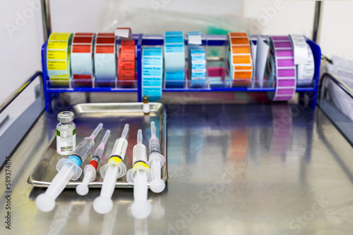 A medical syringe with a colorful tag label on stainless tray in hospital.Drug preparation for patient sedation before surgery with blur background.Close up macro photo of syringes with medicine. photo