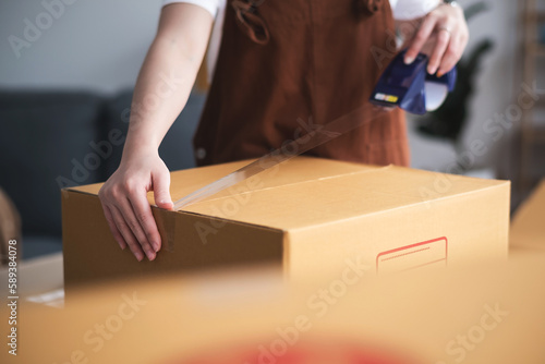 New house, asian woman sealed box while feeling proud and excited about buying a house with a mortgage loan. Young asian woman first time buyers unpacking in dream home or apartment © qOppi