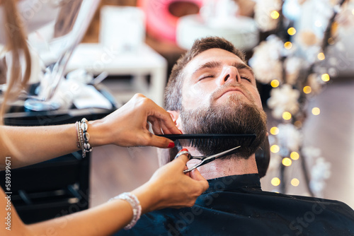 Hands of a hairdresser cutting the beard of a man