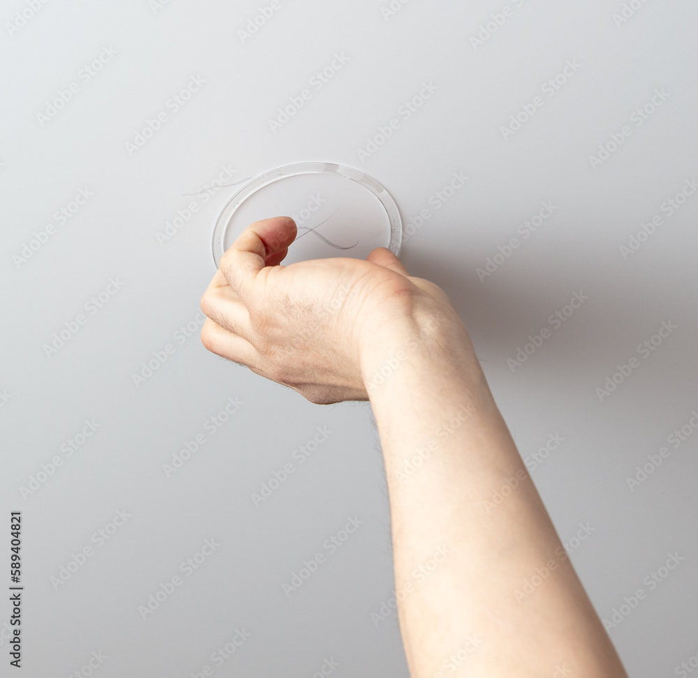 A worker installs a light bulb in a stretch ceiling A worker installs a light bulb in a stretch ceiling