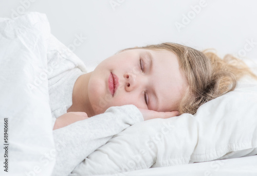 Cute little girl sleeps on the bed at home