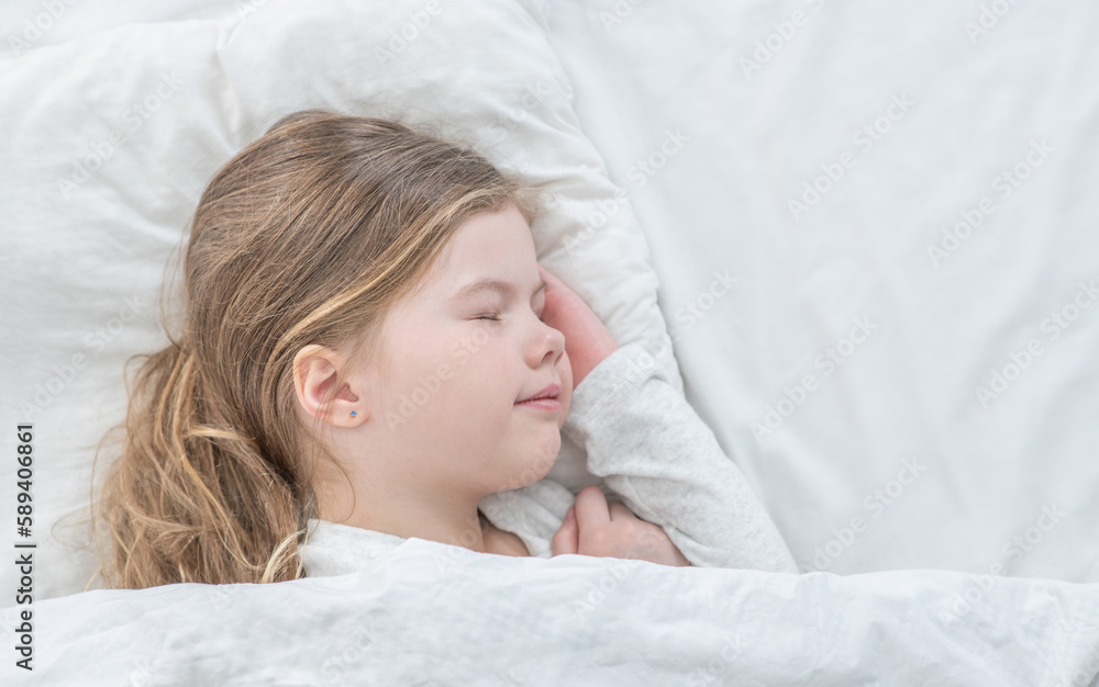 Smiling little girl sleeps on the bed at home. Top down view. Empty space for text Smiling little girl sleeps on the bed at home. Top down view. Empty space for text