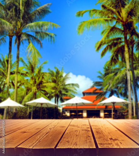 Fototapeta Naklejka Na Ścianę i Meble -  Wood floor or plank table with tropical summer background  resort hotel with patio umbrella and palm tree. Beautiful beach resort and outdoor spa.