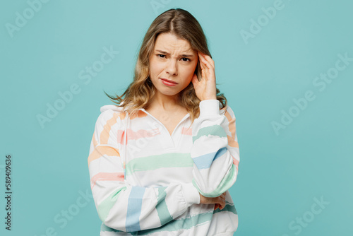 Young sad displeased dissatisfied disappointed caucasian blonde woman wearing hoody looking camera prop up head isolated on plain pastel light blue cyan background studio portrait. Lifestyle concept.