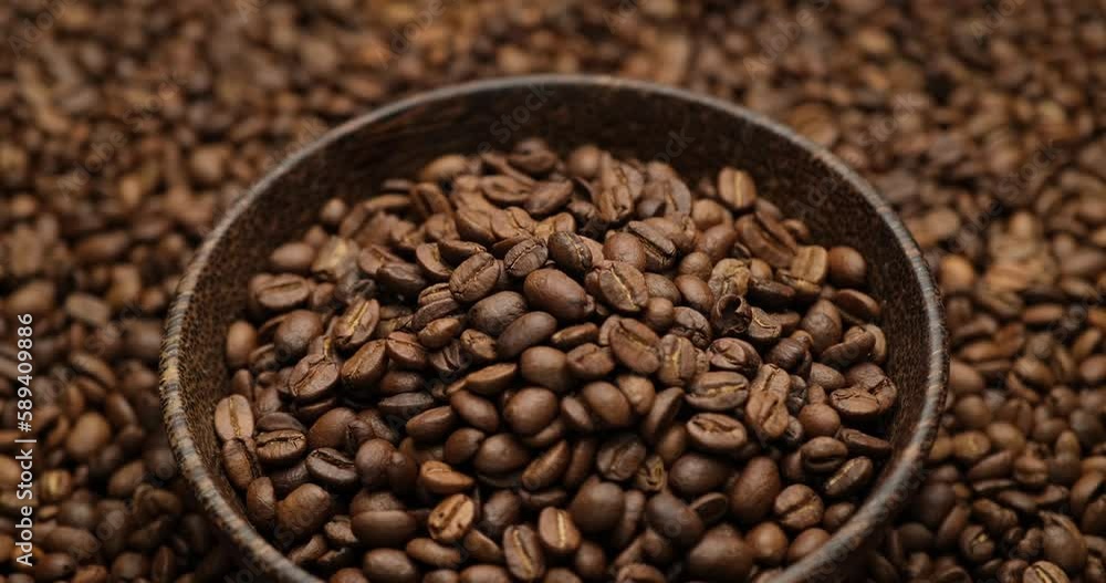 wooden bowl full of coffee beans on a rotating background of fresh roasted coffee beans wooden bowl full of coffee beans on a rotating background of fresh roasted coffee beans