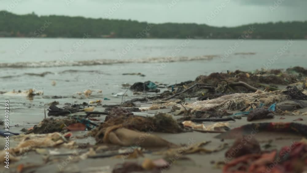 Tropical peninsula beach covered in plastic waste. Ocean waves wash plastic containers ashore and pollute the ecology and the environment. Tropical peninsula beach covered in plastic waste. Ocean waves wash plastic containers ashore and pollute the ecology and the environment.