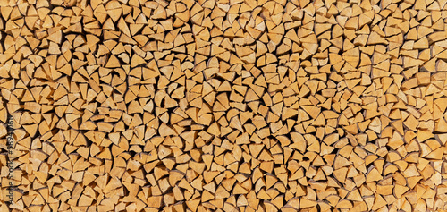 Großer Feuerholz Holzstoß aus vielen kleinen, ordentlich gestapelten braunen Holzscheiten photo