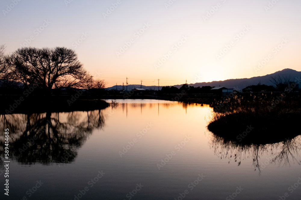 琵琶湖畔にある小さな池の夕暮れ　夕陽に染まる水面