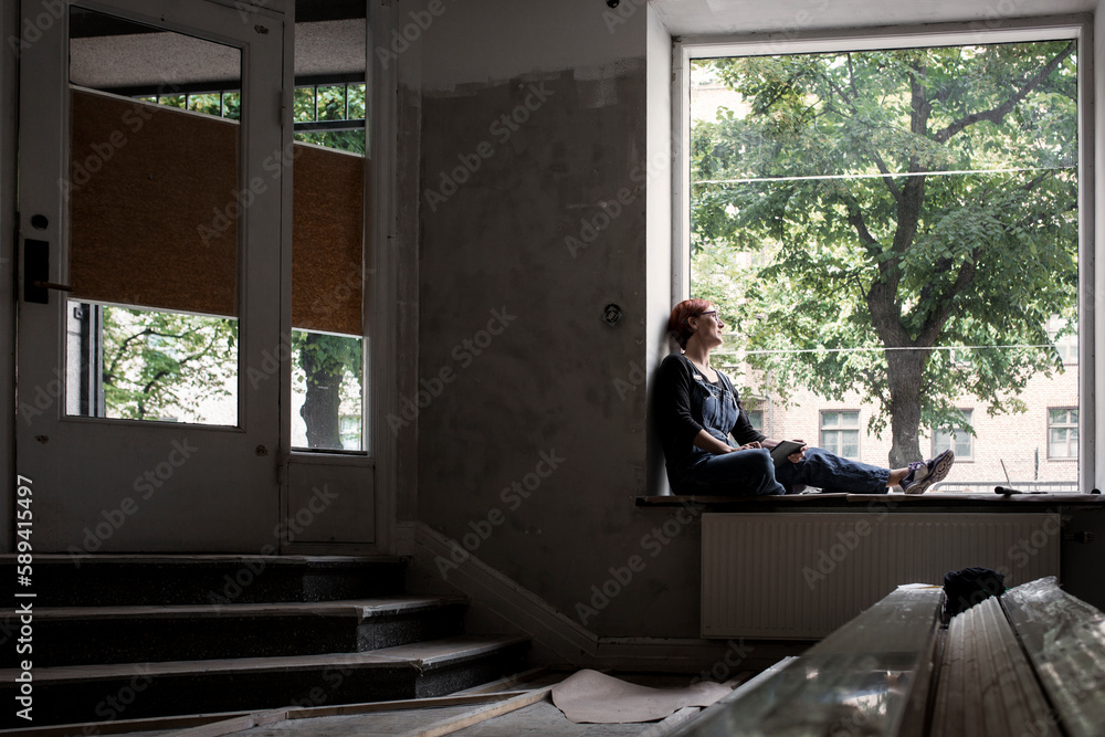 Woman holding digital tablet and looking through window Woman holding digital tablet and looking through window