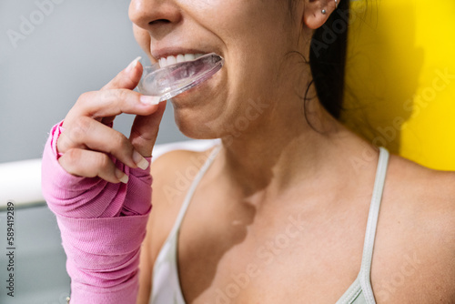 Fototapeta Naklejka Na Ścianę i Meble -  Female athlete putting on a mouth guard in boxing training in a ring