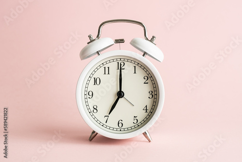 かわいいピンクの背景に白い目覚まし時計 女性らしい時間のイメージ写真
