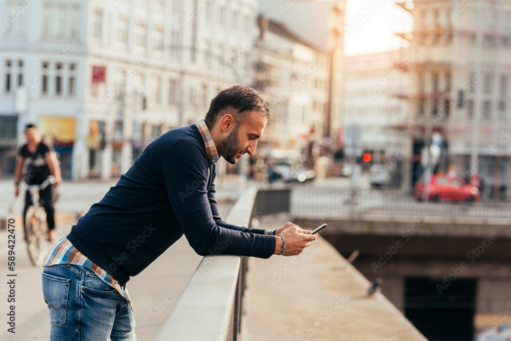 Men standing on city bridge and using smart phone Men standing on city bridge and using smart phone