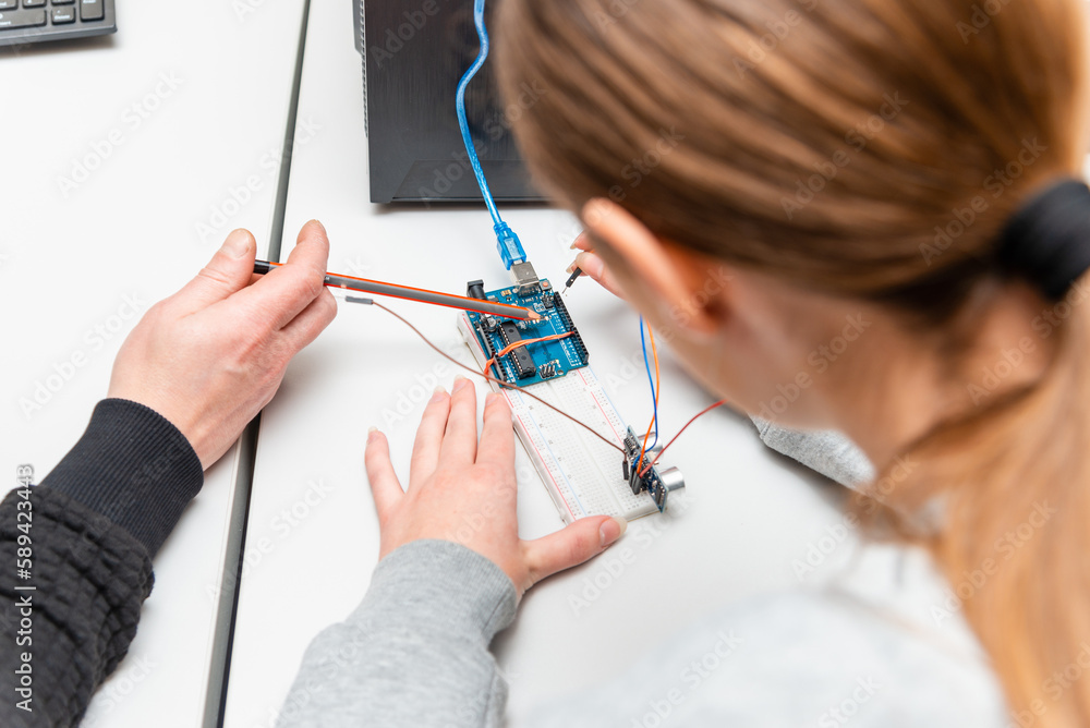 Teacher helping his teen student with diy robot on stem education class ...