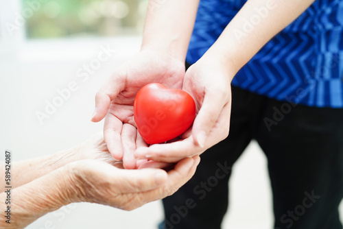 Asian young boy give red heart to old grandmother with love and care.