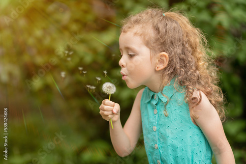 little cute girl blowing on dandelion. concept of summer, vacation, childhood. spring bloom allergy