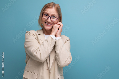 a middle-aged woman with a bob hairstyle in a classic jacket smiles dreamily while standing against a bright background with copy space