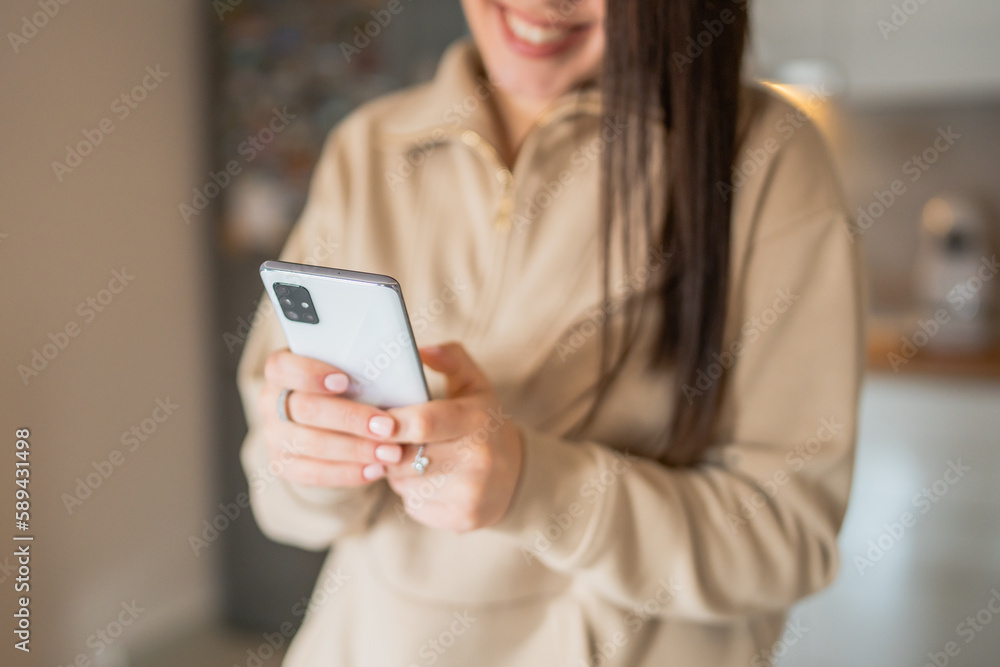 One young woman caucasian using mobile phone at home and smiling, using technology modern lifestyle concept One young woman caucasian using mobile phone at home and smiling, using technology modern lifestyle concept