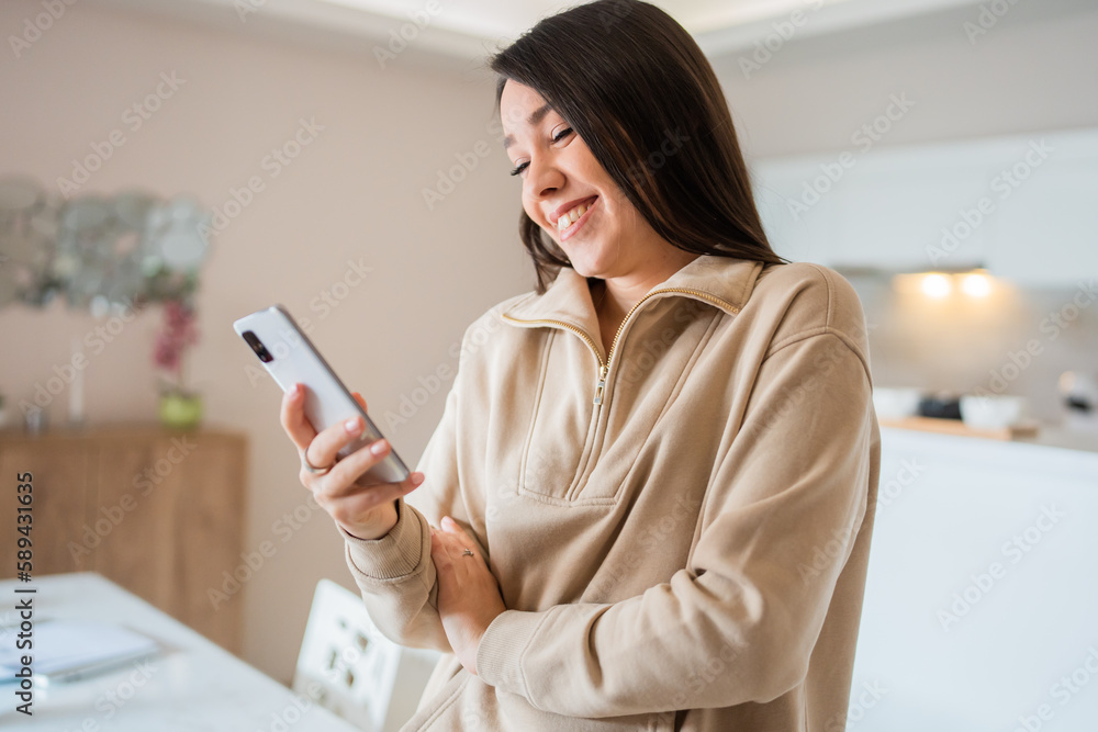One young woman caucasian using mobile phone at home and smiling, using technology modern lifestyle concept One young woman caucasian using mobile phone at home and smiling, using technology modern lifestyle concept
