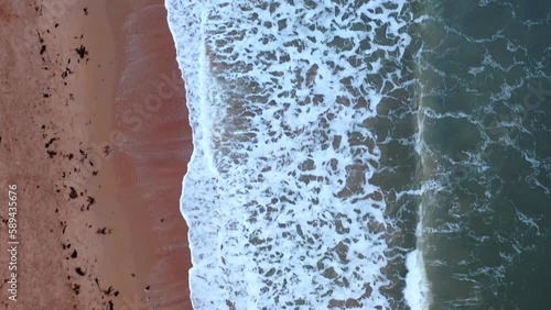 Aerial shot over breaking waves on a Scottish beach at sunset, St Andrews