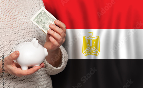 Egyptian woman with money bank on the background of Egypt flag. Dotations, pension fund, poverty, wealth, retirement concept photo