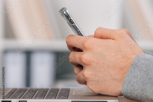 close-up of hands with mobile phone and laptop computer
