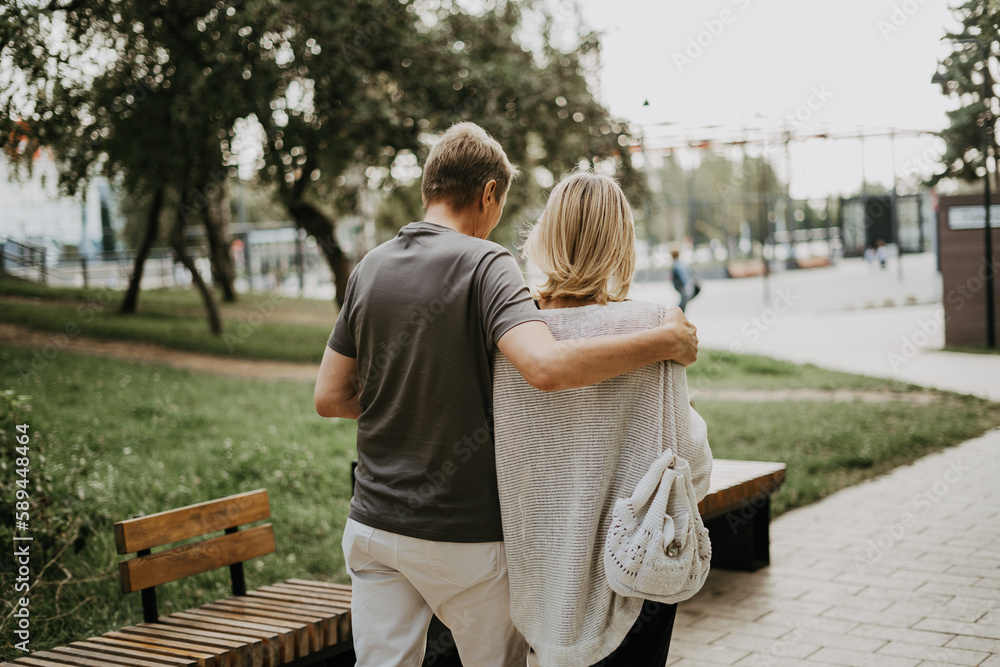 An adult mature happy romantic couple in love outdoors in city street park. A blonde caucasian man and woman spend time together. Senior wife and husband walking outside on town square An adult mature happy romantic couple in love outdoors in city street park. A blonde caucasian man and woman spend time together. Senior wife and husband walking outside on town square