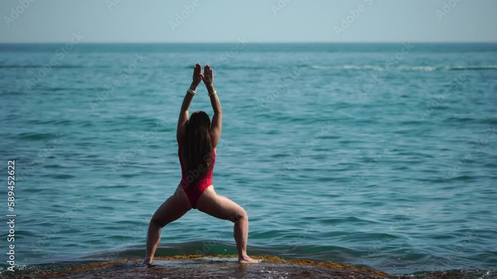 Woman sea yoga. Back view of free calm happy satisfied woman with long hair standing on top rock with yoga position against of sky by the sea. Healthy lifestyle outdoors in nature, fitness concept Woman sea yoga. Back view of free calm happy satisfied woman with long hair standing on top rock with yoga position against of sky by the sea. Healthy lifestyle outdoors in nature, fitness concept