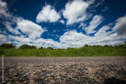 Scenic shot of a rocky road with pasture and beautiful cloudscape in the background
