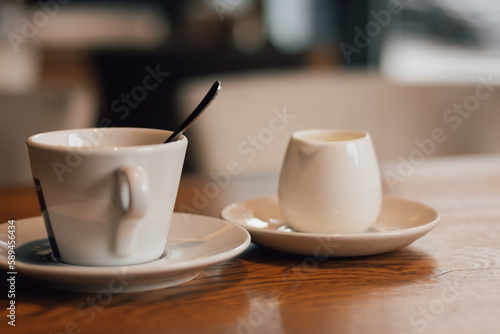Cup of coffee with milk. Morning coffee in cafe. Coffeehouse interior. Hot drinks concept. Espresso with milk sauce and spoon. Coffee time. Americano with milk.