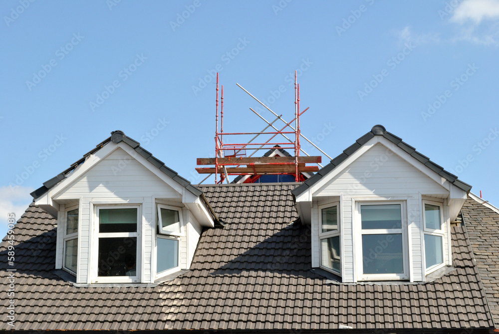 Dormer Windows and Scaffolding on Roof of Building seen against Blue Sky