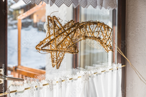 Aus Weiden Holz geflochtener Weihnachtsstern beleuchtet an einem Fenster im Winter zur Weihnachtszeit, Deutschland