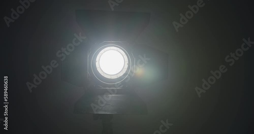Video studio Fresnel lens spotlight on black background. lights slowly turn on and off. Close up.